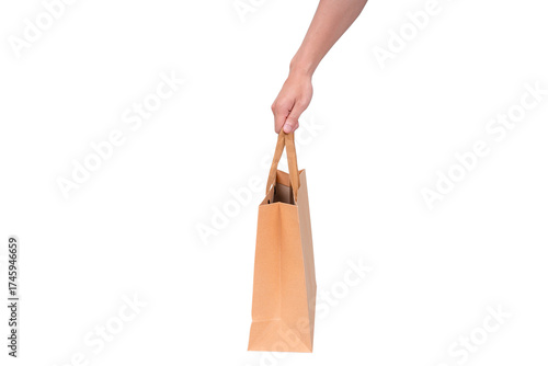 Hand holding a blank brown paper bag, isolated on a transparent background.