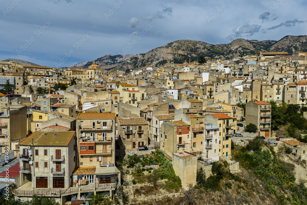 Obraz premium Aerial drone view of Polizzi Generosa, a picturesque Sicilian mountain town perched on rocky cliffs showcasing traditional stone buildings and panoramic views of the Madonie Mountains, Sicily, Italy