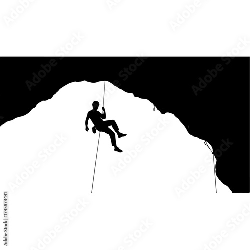 Silhouette of a climber rappelling down a mountain face.