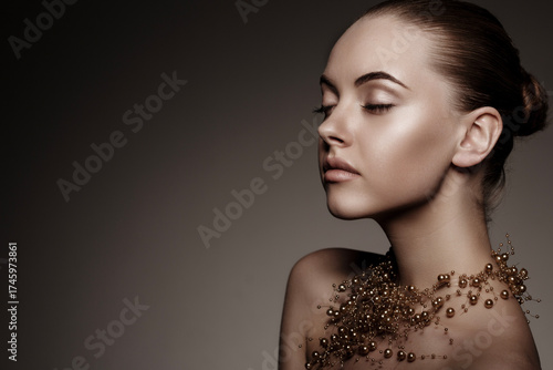 Artistic side profile portrait of a woman with smooth skin and elegant gold pearl necklace. Minimalistic beauty, soft lighting, dark background, luxury and sophistication concept.