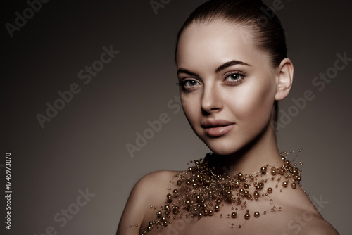 Artistic side profile portrait of a woman with smooth skin and elegant gold pearl necklace. Minimalistic beauty, soft lighting, dark background, luxury and sophistication concept.