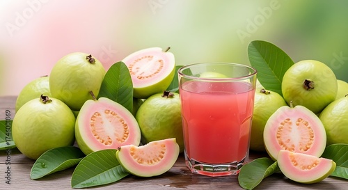 Freshly squeezed pink guava juice in a glass surrounded by ripe guava fruits and green leaves on a wooden table