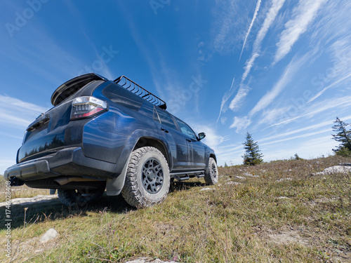 Off-road SUV parked on grassy ridge under vibrant blue sky with streaked clouds in Dolly Sods, West Virginia