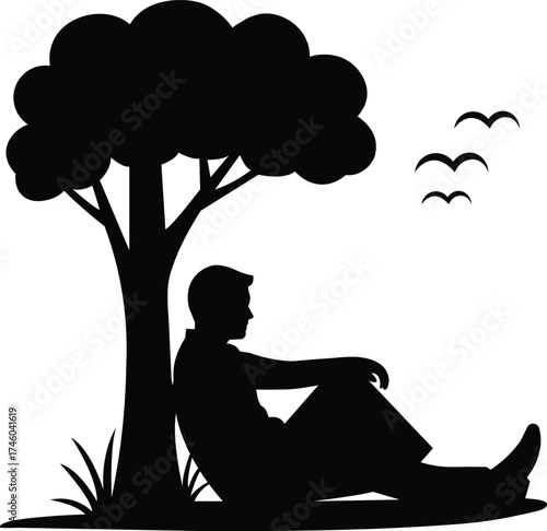 A solitary man sits peacefully under a large tree in silhouette contemplating life with birds flying above in the sky silhouette