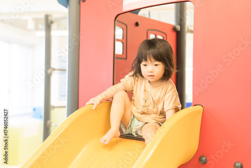 室内の滑り台で遊ぶ女の子の幼児