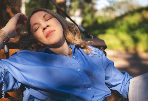 Blonde woman smiles contently resting in a hammock, soaking up the sun in serene garden on a warm summer afternoon.