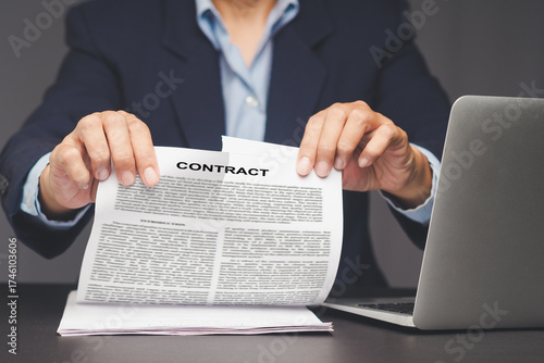 Businessman tearing contract agreement document at office desk.