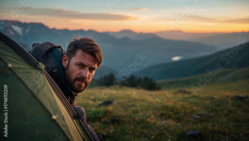 Hiker in tent watching the mountain sunrise.