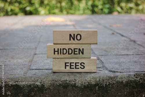 Bold wooden blocks stacked on a pavement spell out 'NO HIDDEN FEES', conveying transparency and straightforward pricing for finance, business, and consumer-focused content.