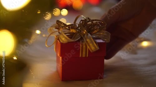 Hand woman putting red gift box on white wool with bokeh lights in christmas time.
