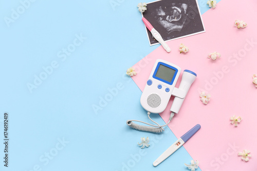 Fetal doppler with sonogram image, pregnancy tests and flowers on color backg...