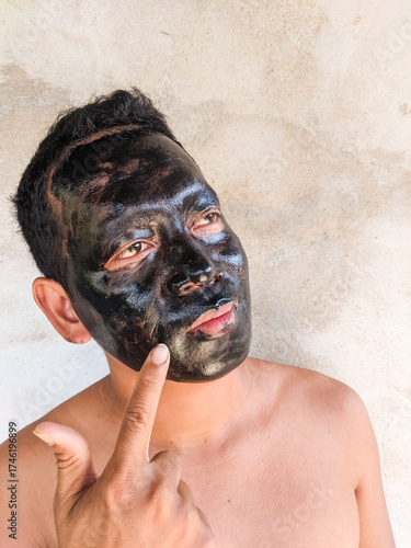 An Asian man using a facial treatment mask