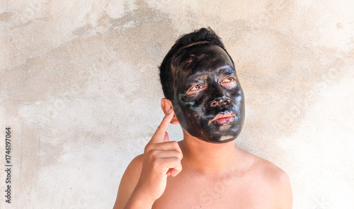 An Asian man using a facial treatment mask