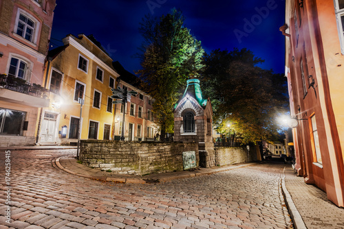Tallinn Old Town cobblestone street with historic buildings and Tiny chapel at night