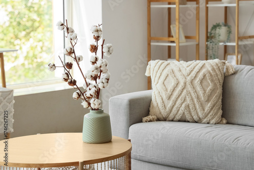 Vase with cotton flowers on table in modern living room
