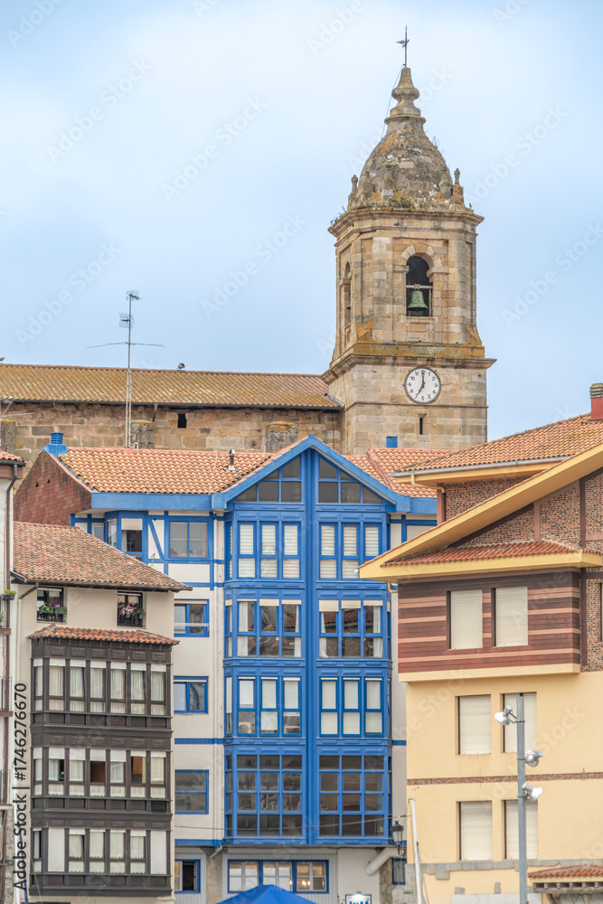 Fototapeta premium Traditional Colorful Buildings with Church Tower in Bermeo, Basque Country Spain, Blue Enclosed Balconies, Stone Bell Tower Historic Buildings