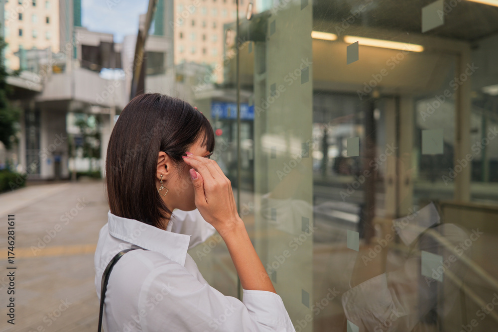 Fototapeta premium Woman in business attire fixing her hairstyle while looking at her reflection