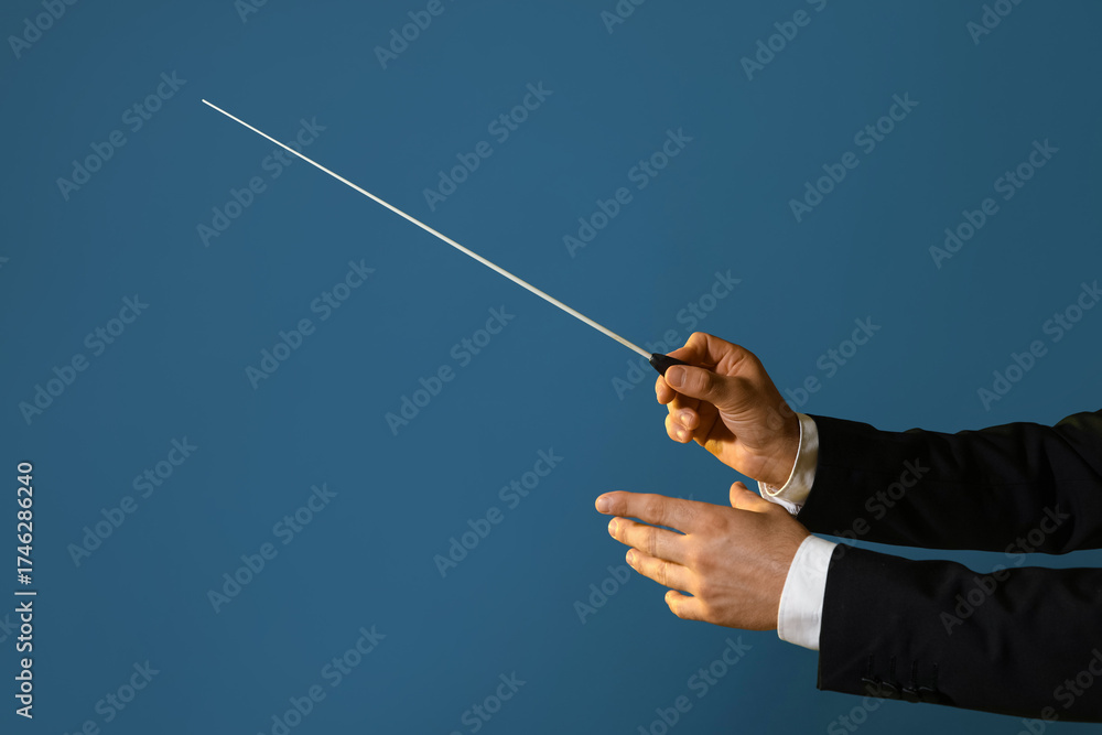 Fototapeta premium Hands of male conductor with baton on blue background