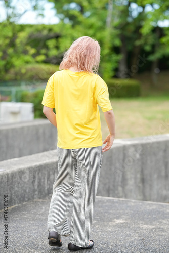 Canvas Print A woman in a yellow shirt and black and white pants walks down a sidewalk
