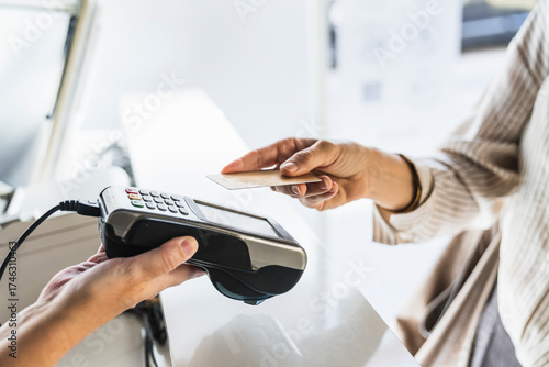 Customer making a payment using a credit card with contactless technology at a pos terminal. Transaction on a counter