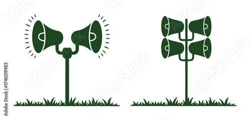 Two sets of green loudspeakers on poles with grass at the base