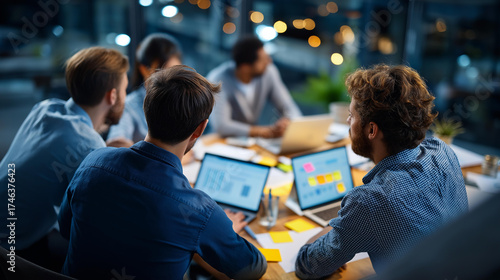 Top view of leadership team sprint meeting laptops and sticky notes visible heads partially out of frame table edges vignetted and surroundings defocused agile sprint planning