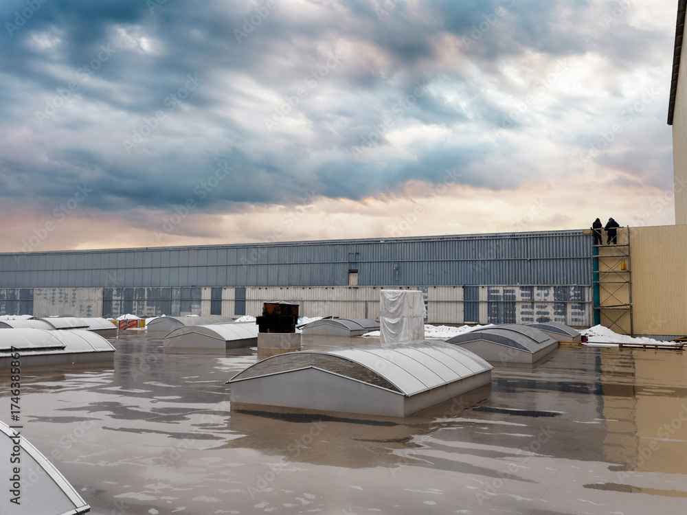 Fototapeta premium Industrial rooftop scene with workers and dramatic sky