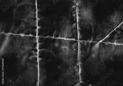 Grunge texture of black folded paper with visible crease lines and distressed surface. Perfect for vintage design backdrop, backgrounds, overlays, and creative projects.