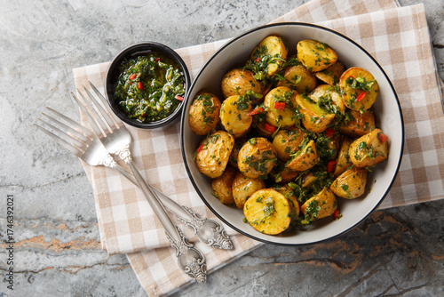 Crispy baked Potatoes with Chimichurri closeup on the plate on the table. Horizontal top view from above