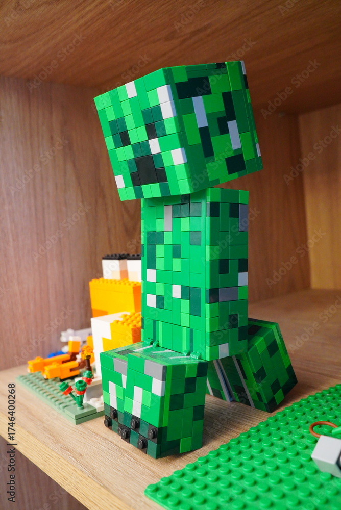 Obraz premium A LEGO model of a Creeper from the popular video game Minecraft displayed on a wooden shelf