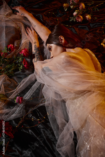 Young woman in chiffon dress surrounded by flowers in a romantic bathtub setting
