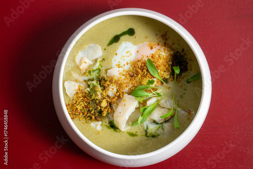 Traditional Portuguese codfish soup 'Açorda de Bacalhau', crafted by a chef, featuring bread, boiled egg, garlic, olive oil, and herbs in a gourmet presentation.