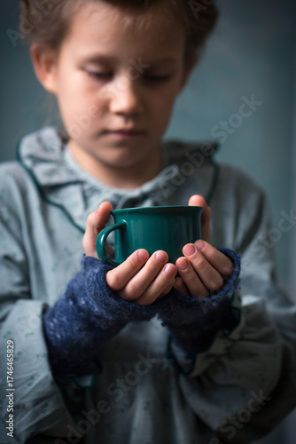 A girl is holding a green cup in her hands
