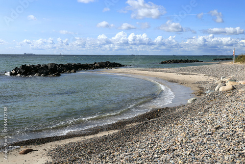 Landscape photo with a view of a bay of sea, a pebble beach and a blue sky with clouds at Cape Grenen, in Skagen, northern Denmark