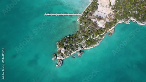 Top-down aerial view of a rocky peninsula with a pie and gazebo.