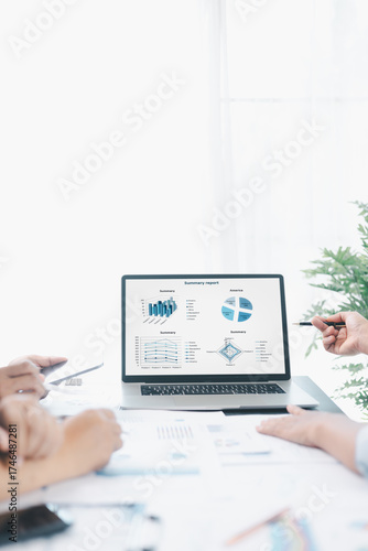 Business data analysis concept with colleagues reviewing financial report on laptop, pointing at chart with growth graph, teamwork discussing statistics, planning strategy and corporate success.