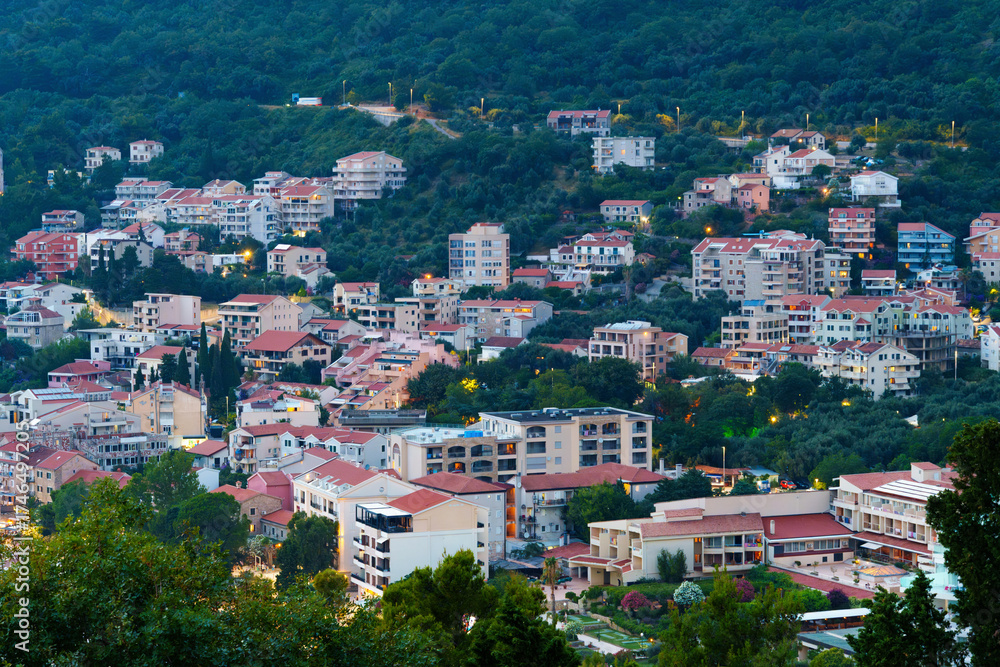Fototapeta premium Panoramic view of resort town, Petrovac, Montenegro, from observation point during sunset, architecture and street lights, beautiful forested mountains, a beautiful resort
