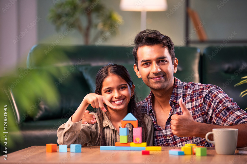 Obraz premium Indian father and daughter building wooden toy tower, spending quality time together