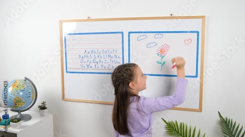Cute schoolgirl draws a red heart on a magnetic whiteboard using markers during an art activity. Educational and creative video concept showing children developing imagination and skills.