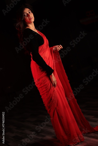 Portrait of an Indian Nepali woman in red traditional saree and black blouse under warm indoor lighting