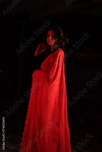 Portrait of an Indian Nepali woman in red traditional saree and black blouse under warm indoor lighting