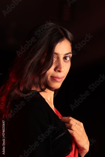 Portrait of an Indian Nepali woman in red traditional saree and black blouse under warm indoor lighting