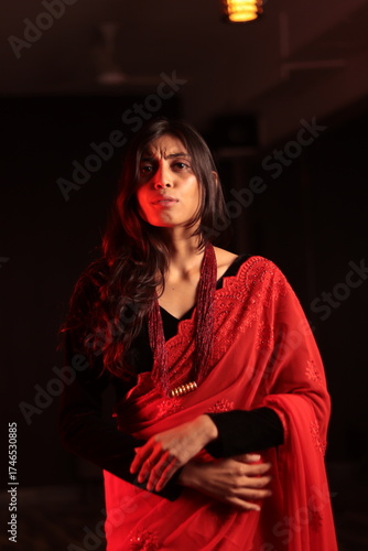 Portrait of an Indian Nepali woman in red traditional saree and black blouse under warm indoor lighting
