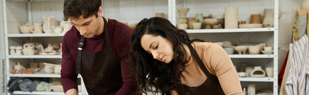 Fototapeta premium Young couple shares a creative moment while crafting pottery in a cozy studio