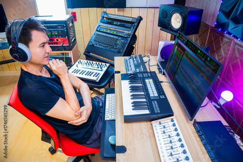 asian male music producer, sound engineer, composer, musician. artist enjoy listening his song in home studio.