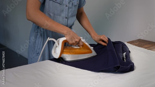 Unrecognizable woman ironing a man's shirt at home. Domestic life chore.