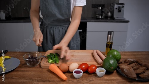 Woman preparing breakfast. Chopping vegetables, cucumber, carrot, tomato, avocado on board.