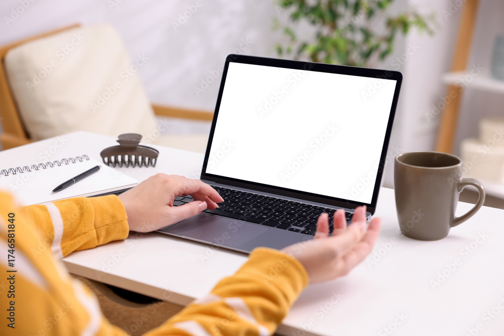 Fototapeta premium Woman working with laptop at white table indoors, closeup. Mockup for design