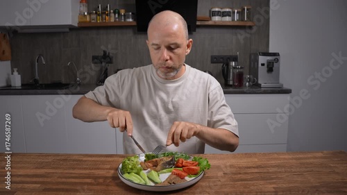 Balanced mediterranean dinner for health. Middle-aged bald man eating at home kitchen.