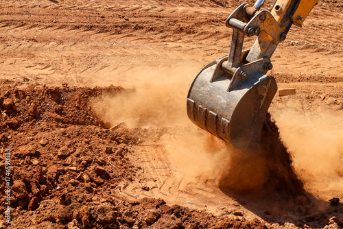 Foto Excavator bucket digging soil on construction site